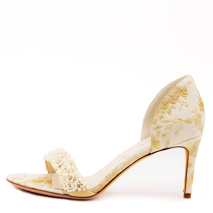 A satin d'orsay heel shoe with a floral pearl embellishment, in a beige or light gold color, with a stiletto heel.