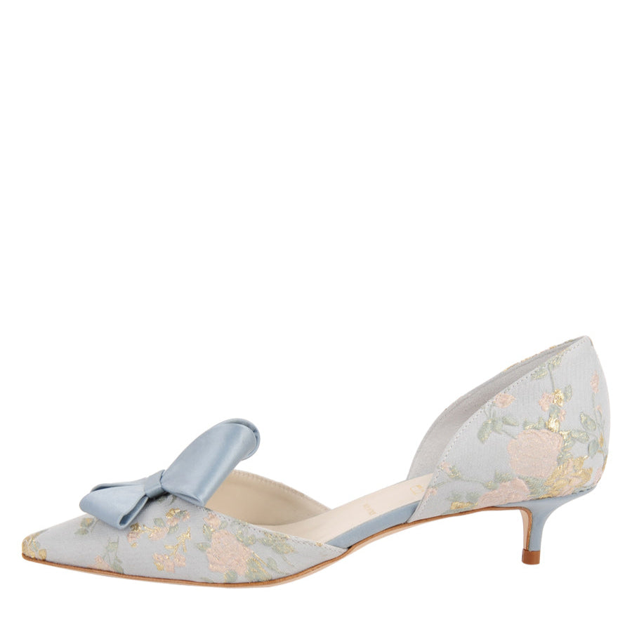 A pointed toe d'Orsay evening shoe with a kitten heel, featuring a blue and white floral pattern and a bow detail on the top.