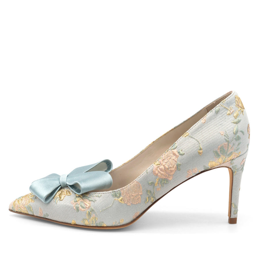 A pointed toe satin pump with a fabric upper, leather lining, and sole, in pearl blue with a floral pattern and a bow detail.
