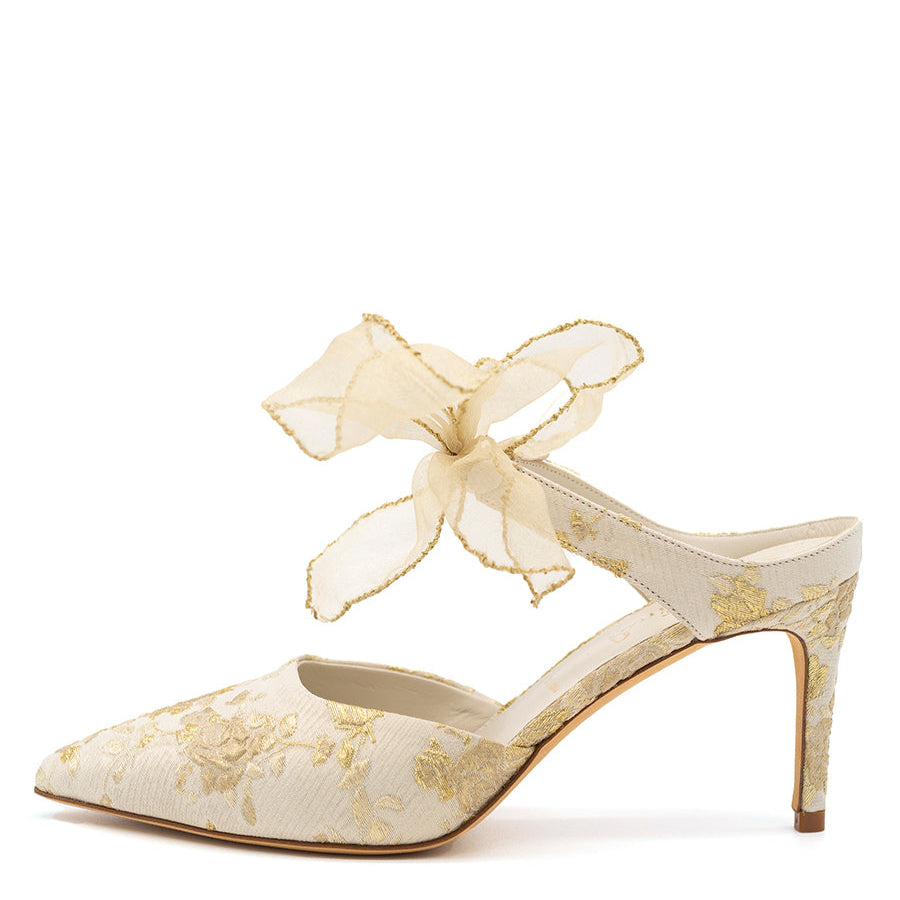 A white pointed toe pump with a sheer bow detail on the ankle, featuring a stiletto heel.