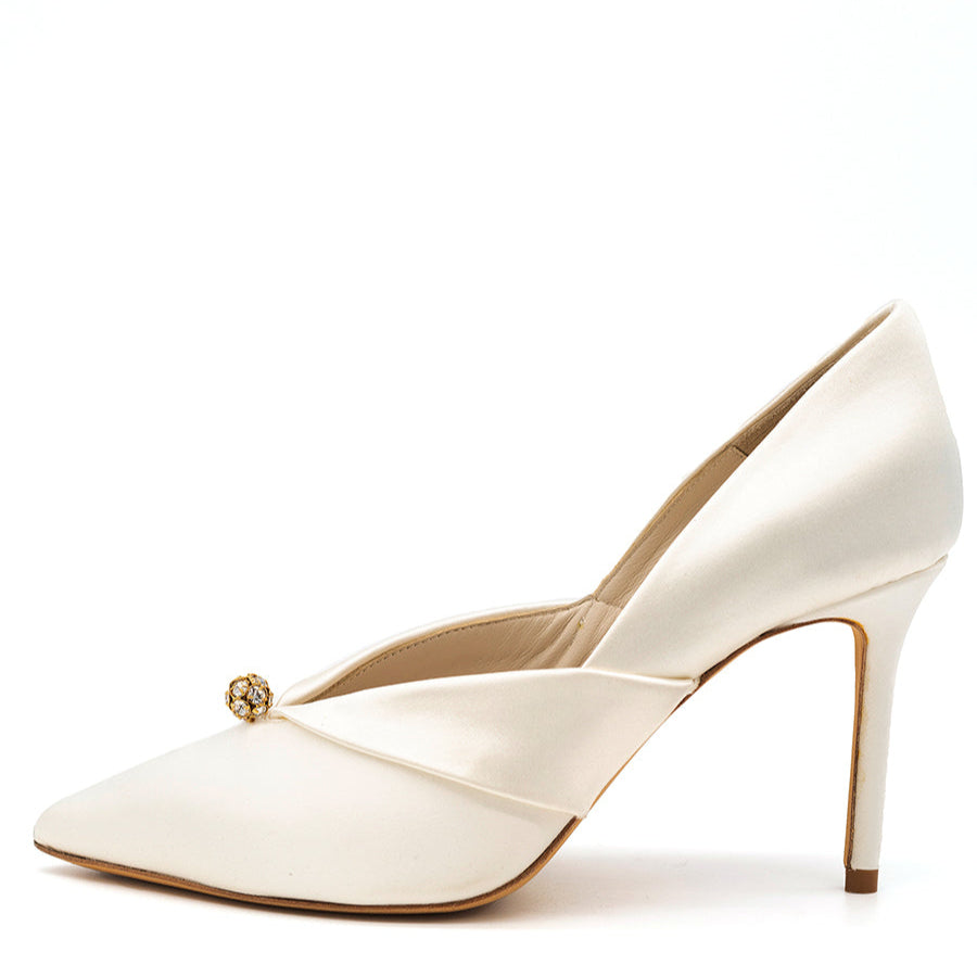 A white pointed toe pump with a high heel and satin finish, featuring crystal embellishments and a folder over fabric detailing.